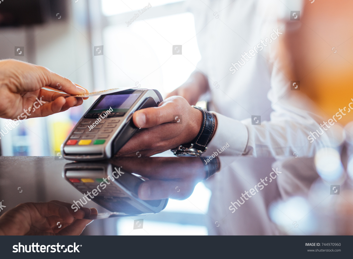 Hand of customer paying with contactless credit card with NFC technology. Bartender with a credit card reader machine at bar counter with female holding credit card. Focus on hands. #744970960