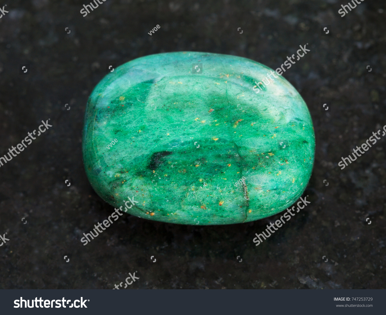 macro shooting of natural mineral rock specimen - polished green beryl gemstone on dark granite background #747253729
