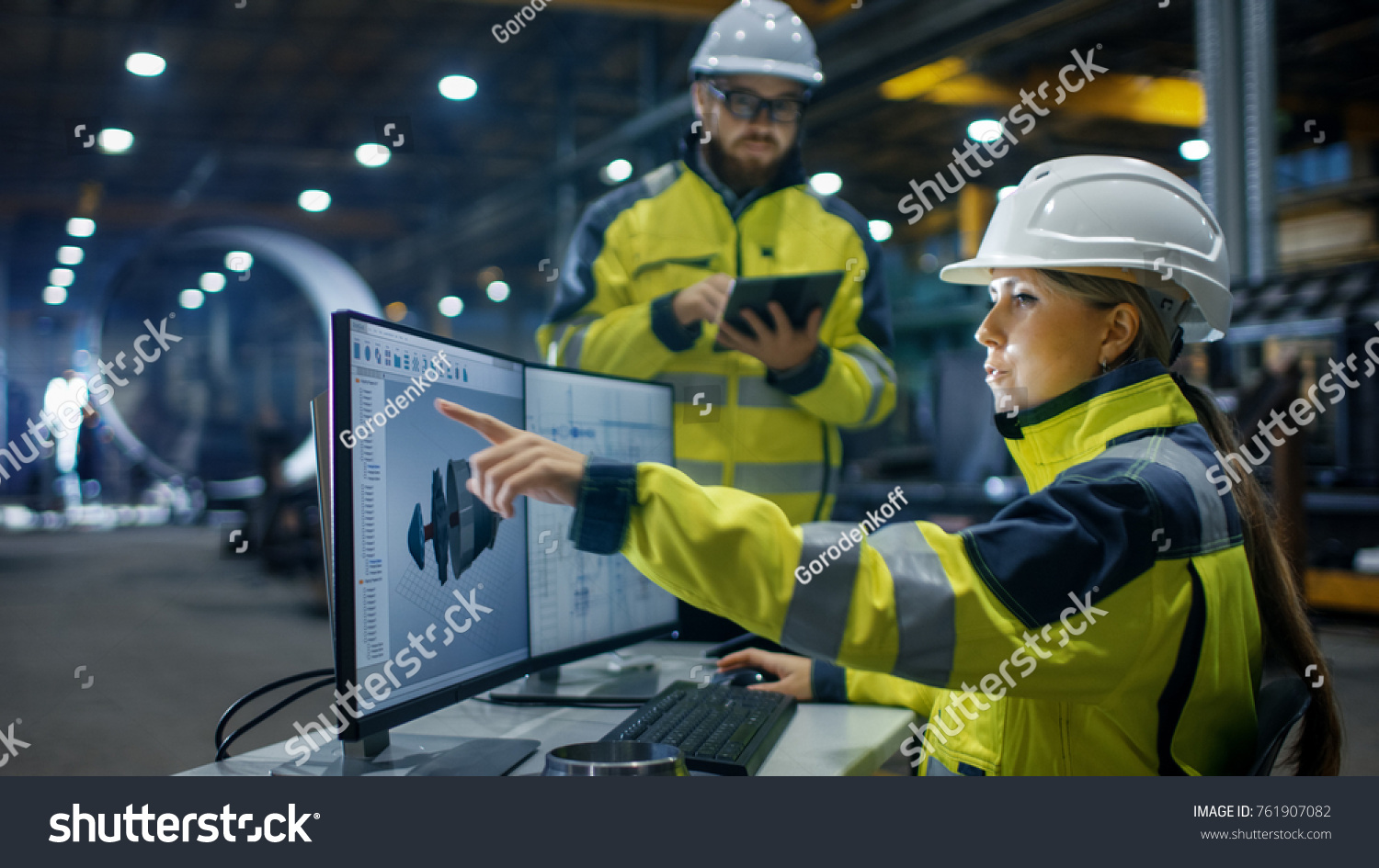 Inside the Heavy Industry, Factory Female Industrial Engineer Works on Personal Computer She Designs 3D Engine Model, Her Male Colleague Talks with Her and Uses Tablet Computer. Low Angle Shot. #761907082