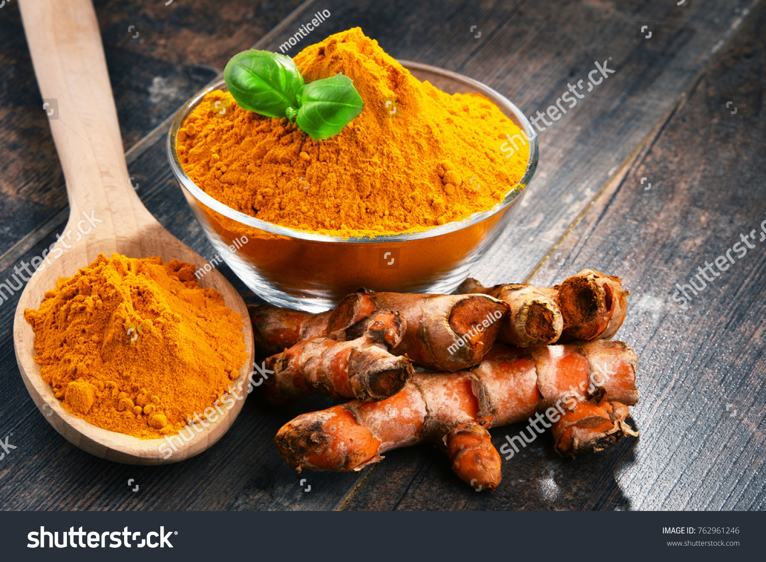 Composition with bowl of turmeric powder on wooden table. #762961246