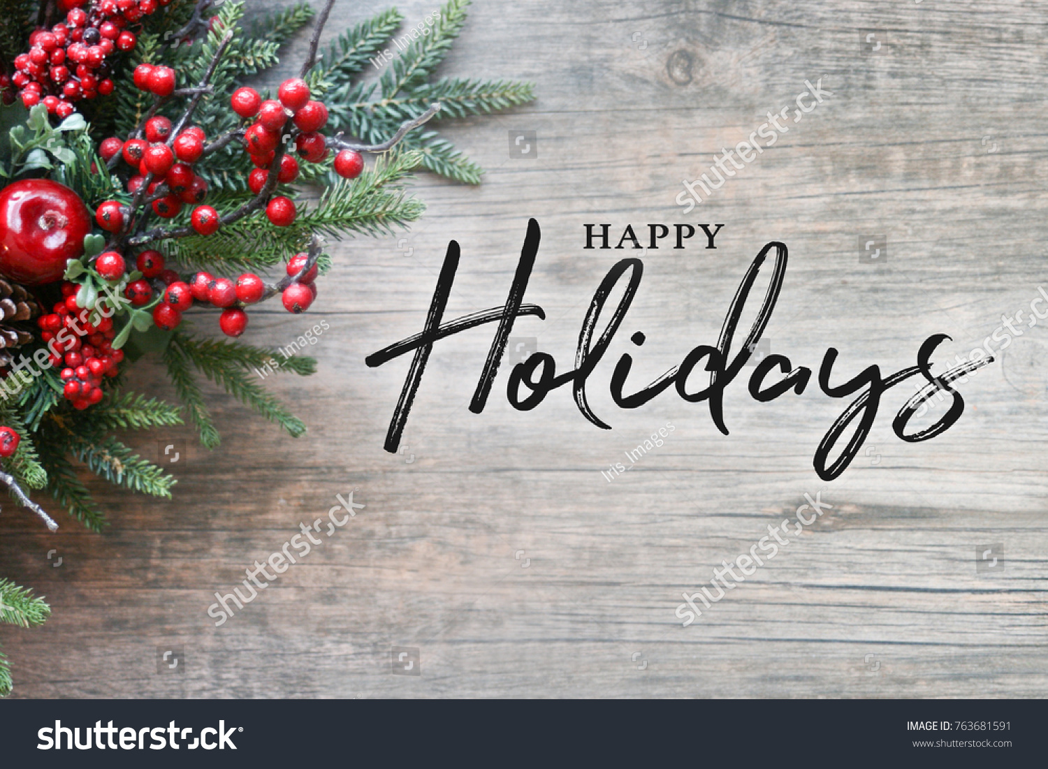 Happy Holidays Text with Christmas Evergreen Branches and Berries in Corner Over Rustic Wooden Background #763681591