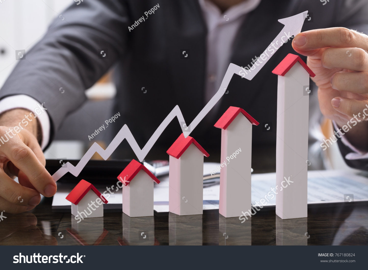 Businessman Holding Paper Graph Over The Increasing House Miniature #767180824