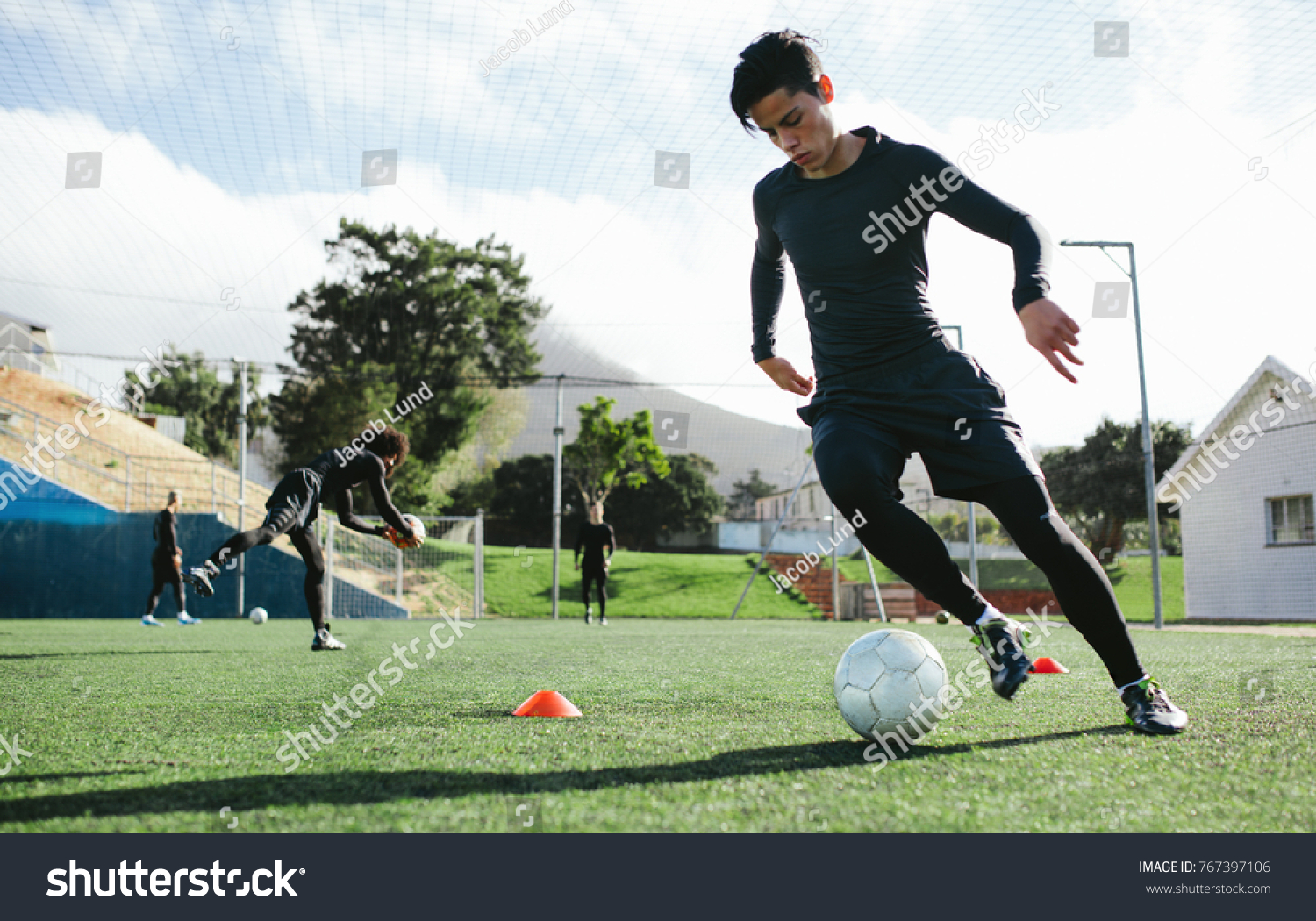Football player training in soccer field. Young soccer player practicing ball control on training session. #767397106