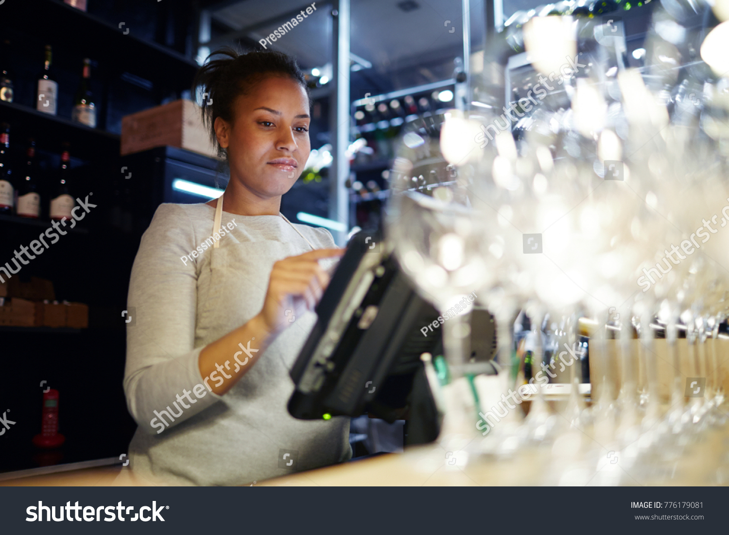 Worker of modern pub, bar or restaurant standing in front of computer monitor and giving new orders to kitchen #776179081