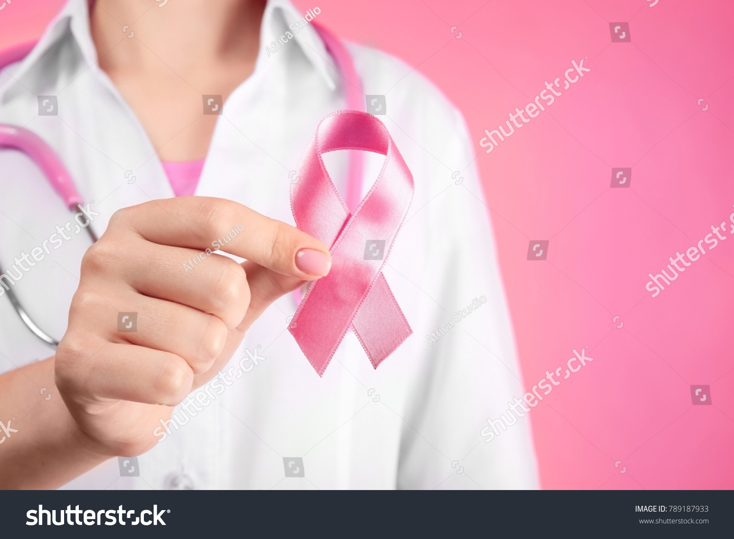 Doctor holding pink ribbon on color background. Breast cancer awareness concept #789187933