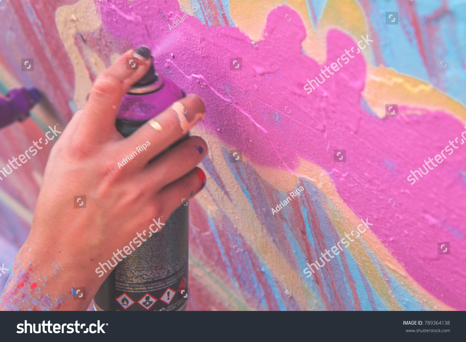 Graffiti artist Hand painting with aerosol spray on the wall, asphalt paint work. Urban man performing with murales - Concept of colourful  modern art - Focus on his hand .graffiti, wall, paint, art,  #789364138