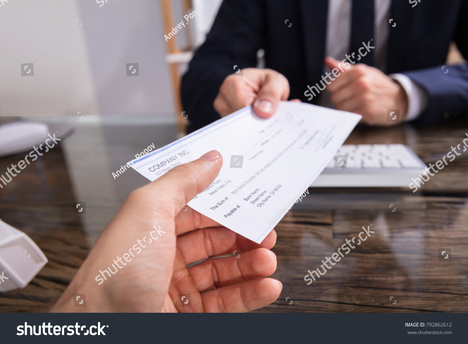 Close-up Of A Businessperson's Hand Giving Cheque To Colleague At Workplace #792862612