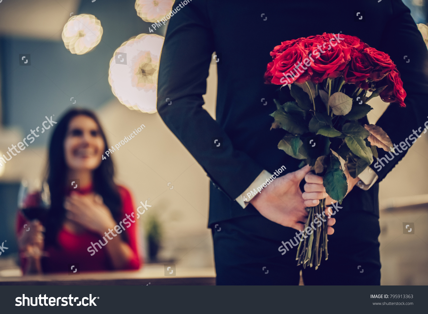 Beautiful loving couple is spending time together in modern restaurant. Attractive young woman in dress and handsome man in suit are having romantic dinner. Celebrating Saint Valentine's Day. #795913363