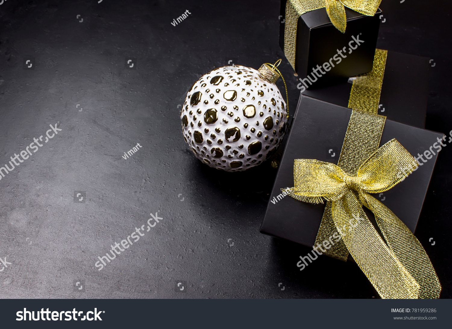 beautiful white and golden christmas ball and black t box with gold ribbon on a black