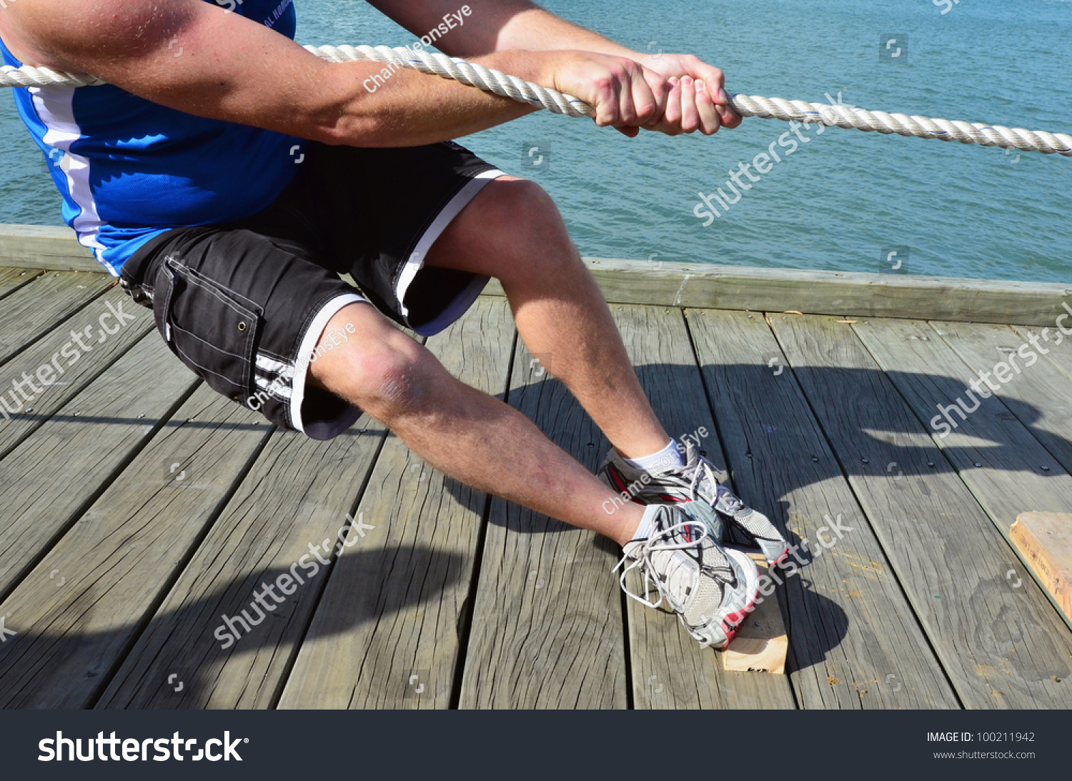 近距离的男性的手和身体拉一根绳子拔河比赛。