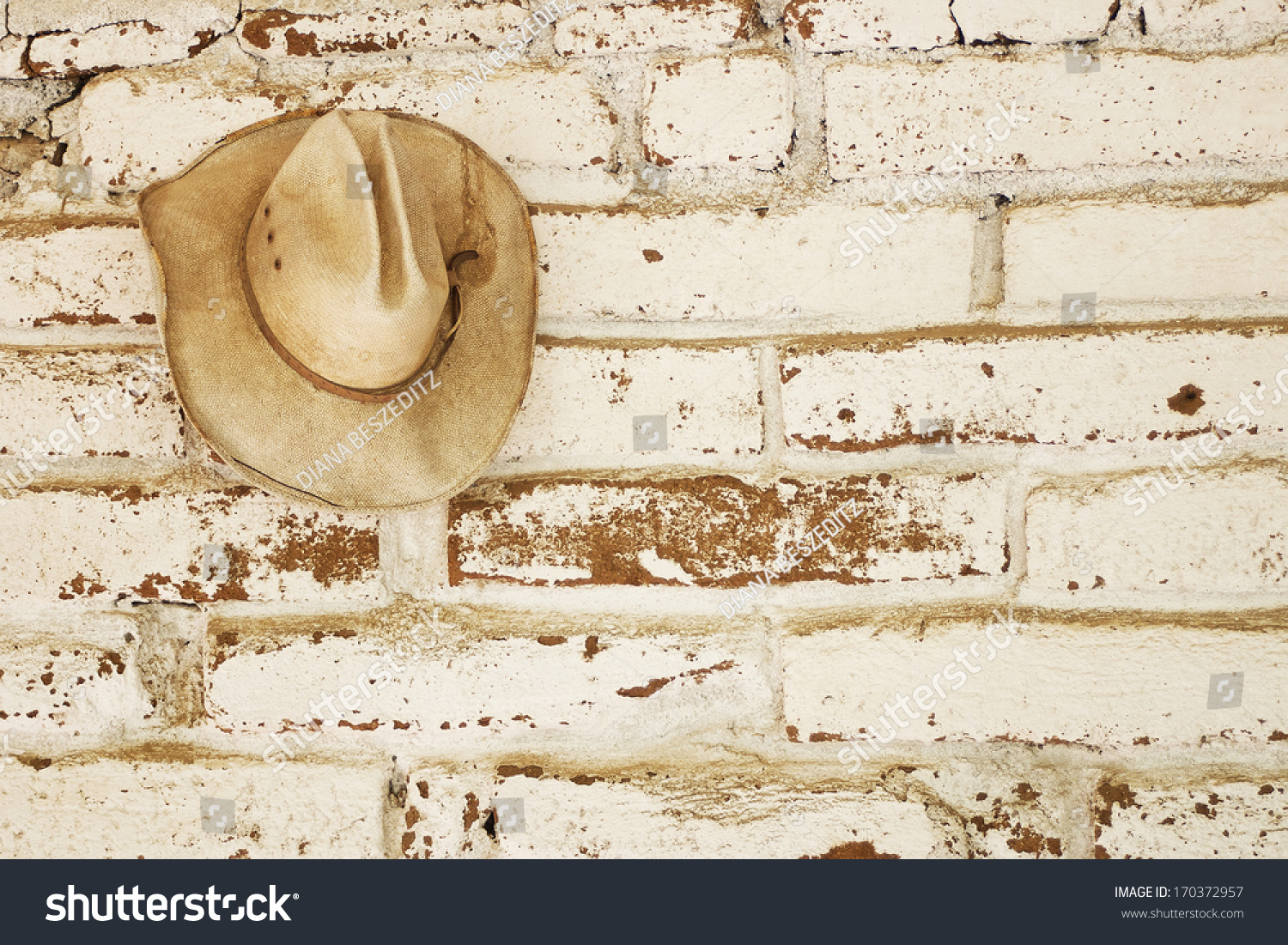 草牛仔帽挂在一个白色的墙砖adobe洗与开放空