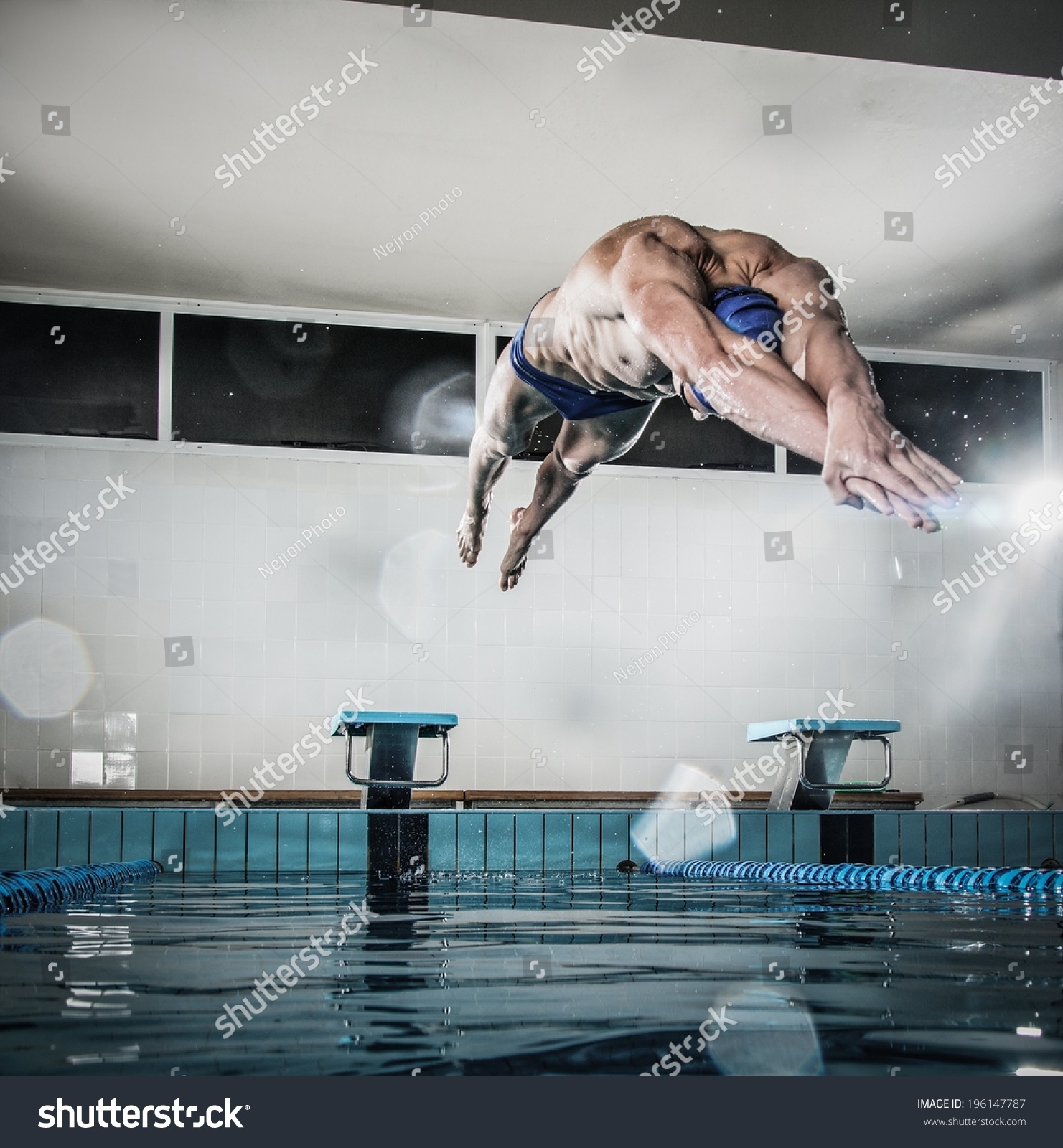 年轻肌肉游泳运动员跳起跑架在一个游泳池 - 人