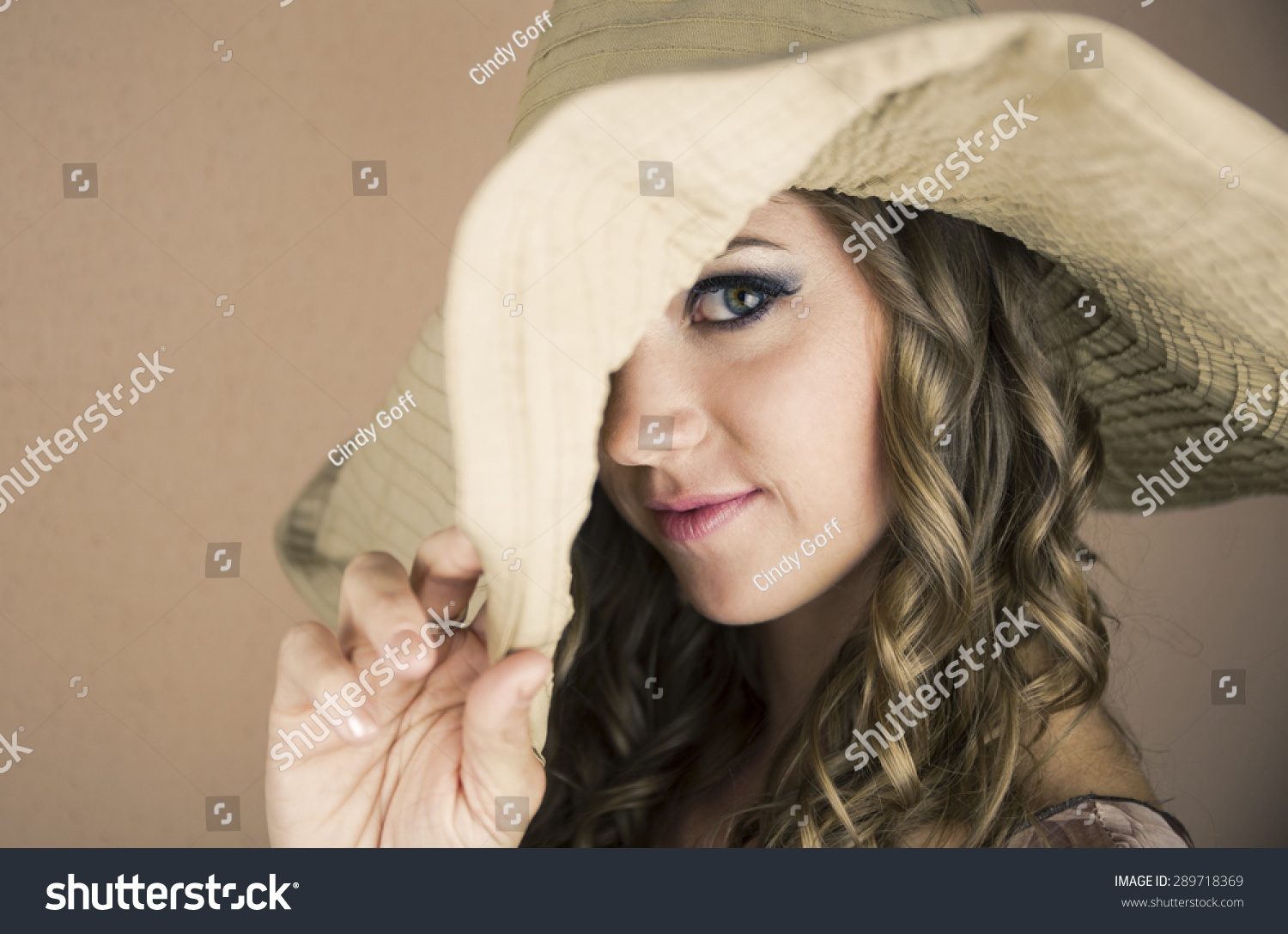 年轻漂亮的女人与大的帽子拉了一只眼睛。-人