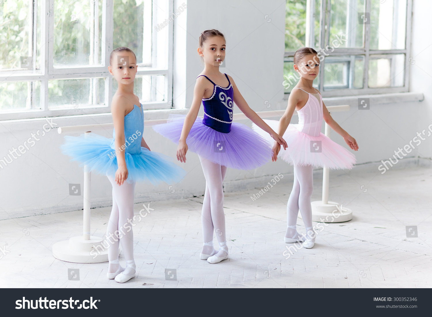 三个小芭蕾女孩在五彩缤纷的图图摆出芭蕾舞横