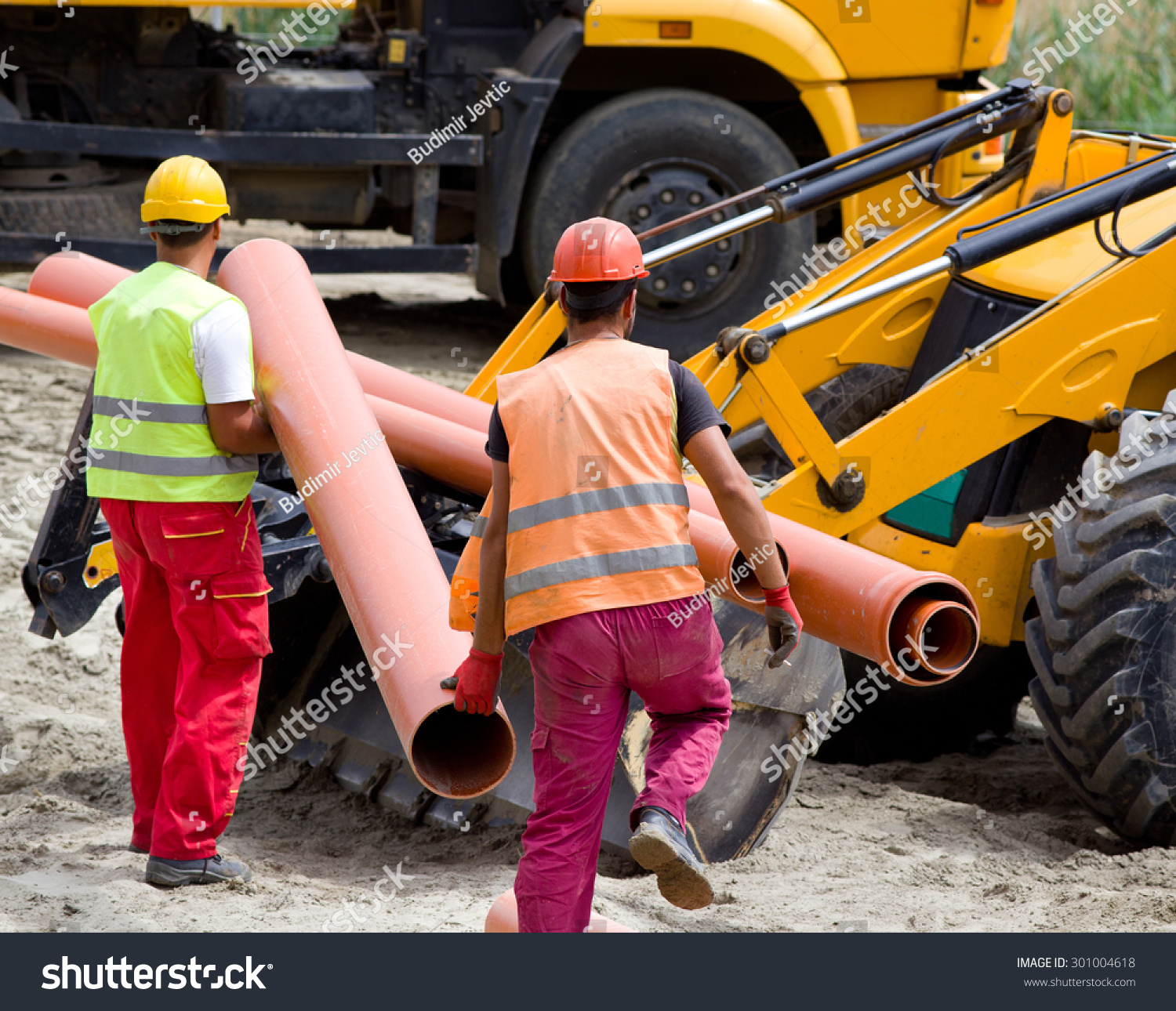 建筑工人安全布管道和加载推土机在建筑工地运