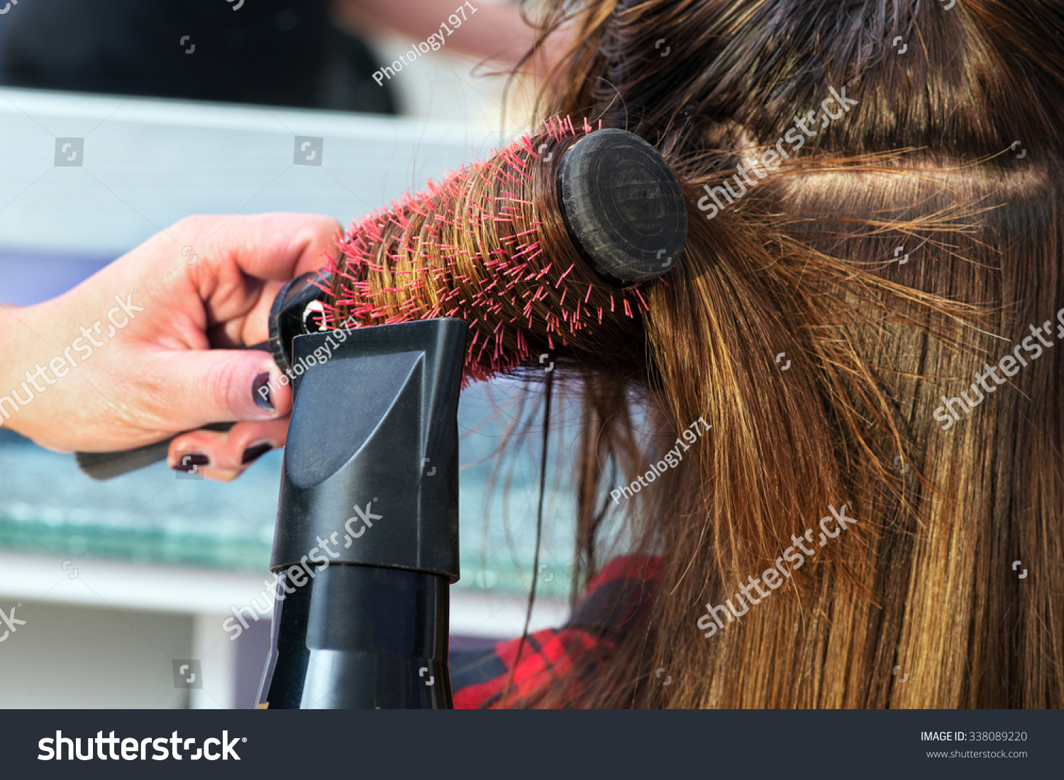 发型师吹干长棕色的头发吹风机和刷在美容沙龙