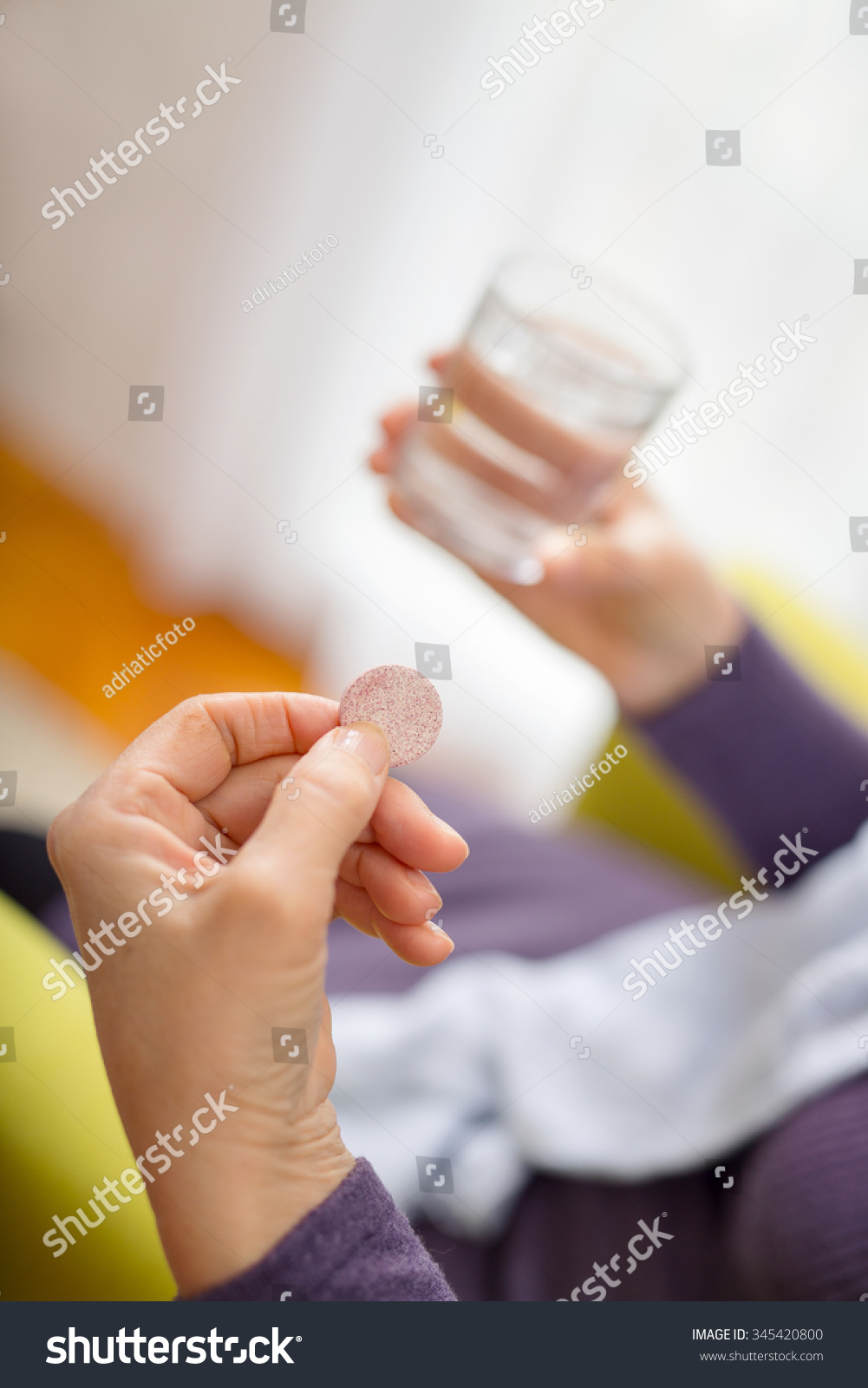 女人服药。女人放弃一个冒泡的抗酸剂在一杯水