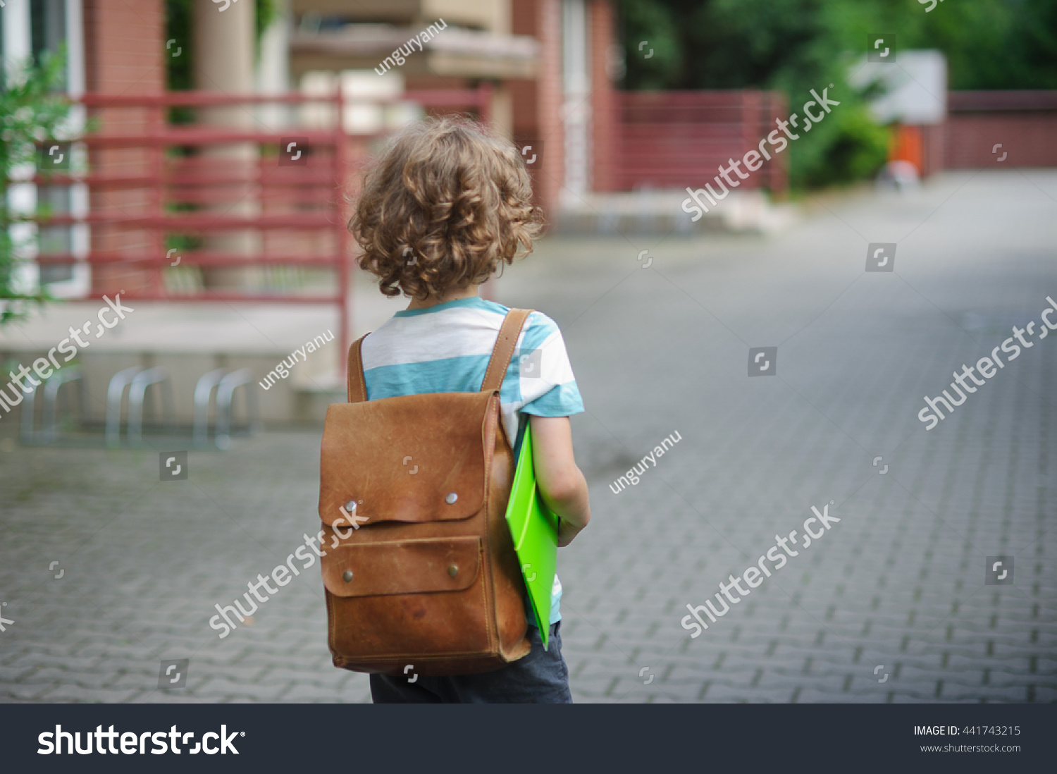 小学生的书包在他的肩膀上,手里拿着一个文件