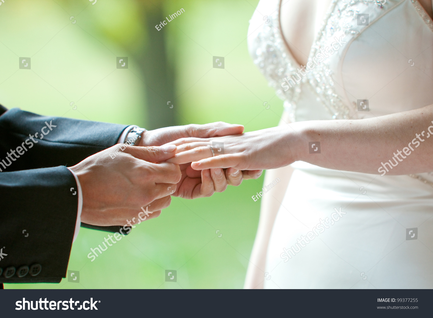 A Man Putting The Wedding Ring On His Brides Finger During A Ceremony