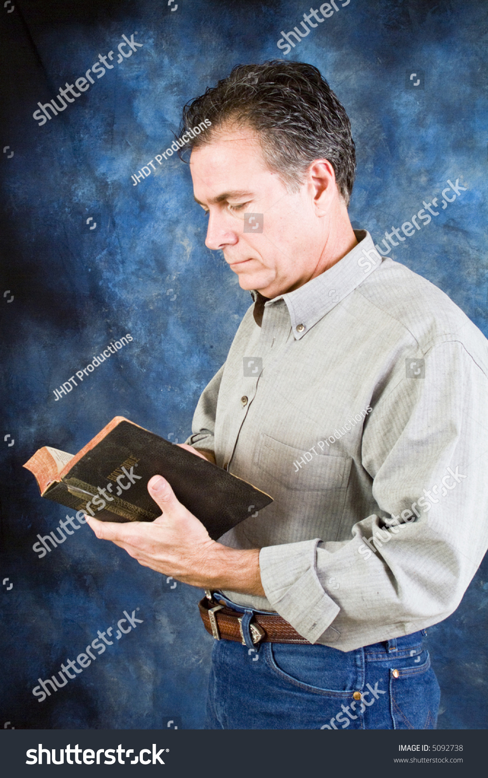 A Man Standing In Front Of A Blue And Gray Painted Backdrop Reading A ...