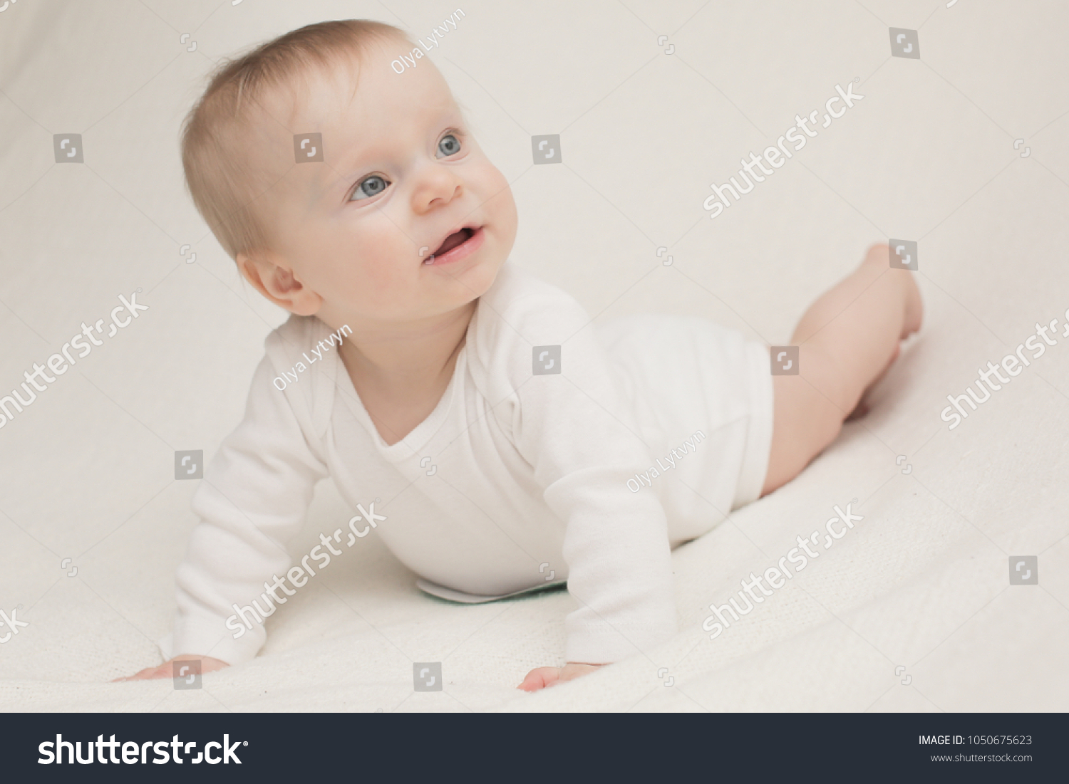 A 8 month old happy baby girl in front of a white background blonde