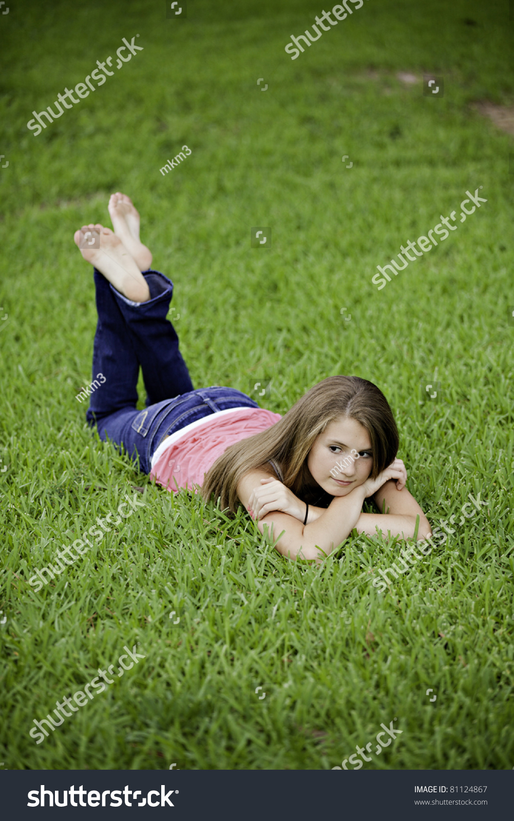 A Pretty Teenage Female Girl Laying Face Down On Green Grass Looking ...