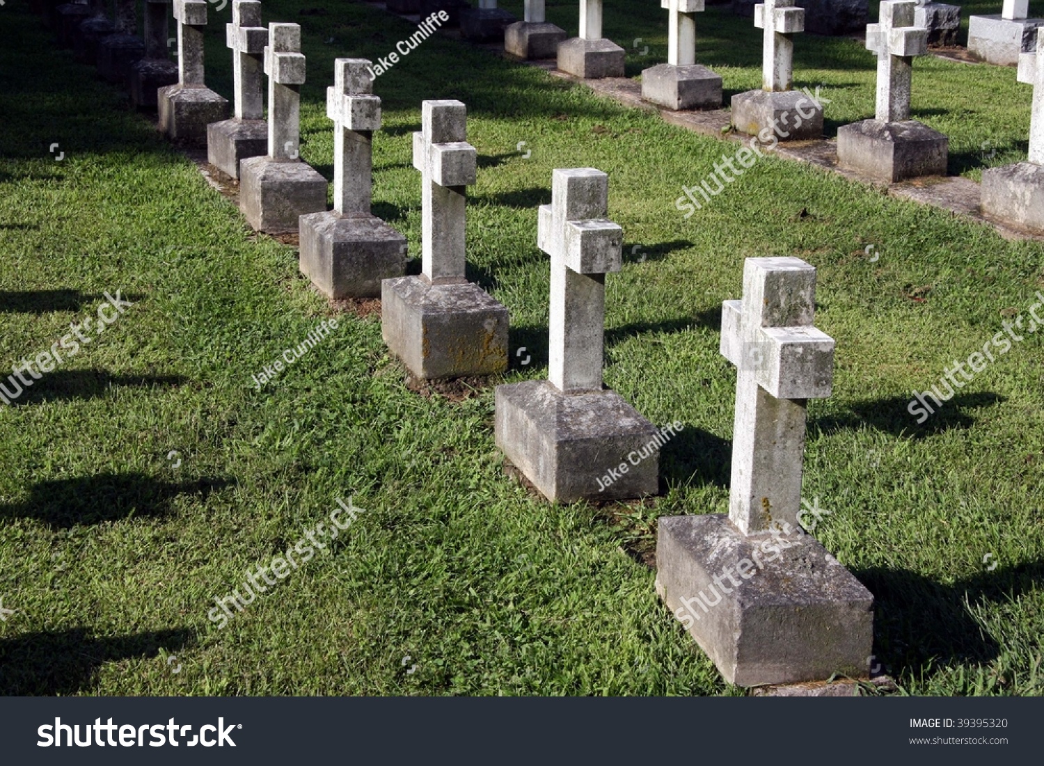 A Row Of Stone Cross Shaped Tombstones Are Illuminated By The Setting ...