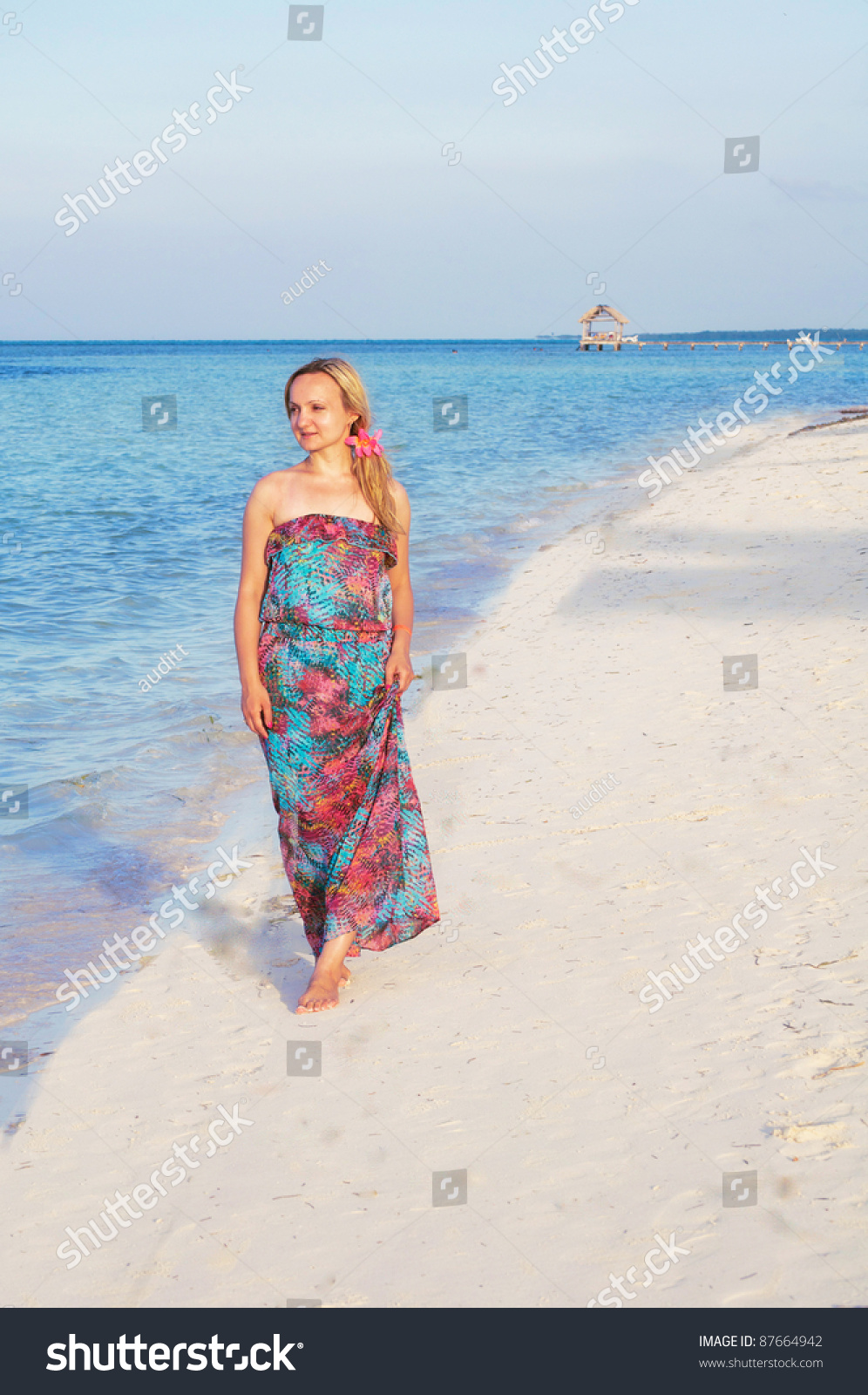 A Young Woman In Maxi Dress Is Walking Along The Beach Stock Photo ...
