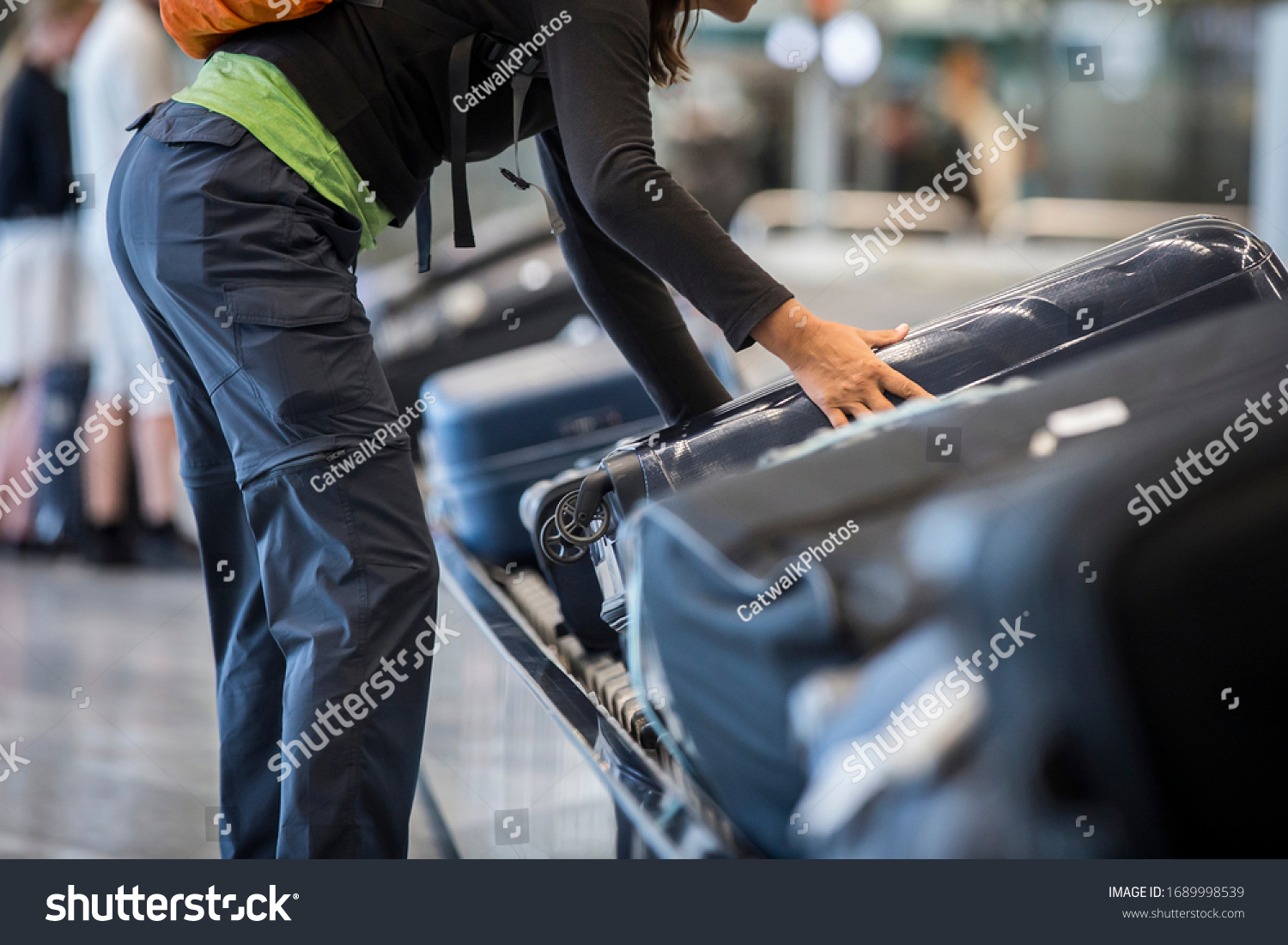 Stock Photo An Unidentified Woman Collecting A Wheeled Suitcase From A Luggage Belt At The Airport Terminal 1689998539 