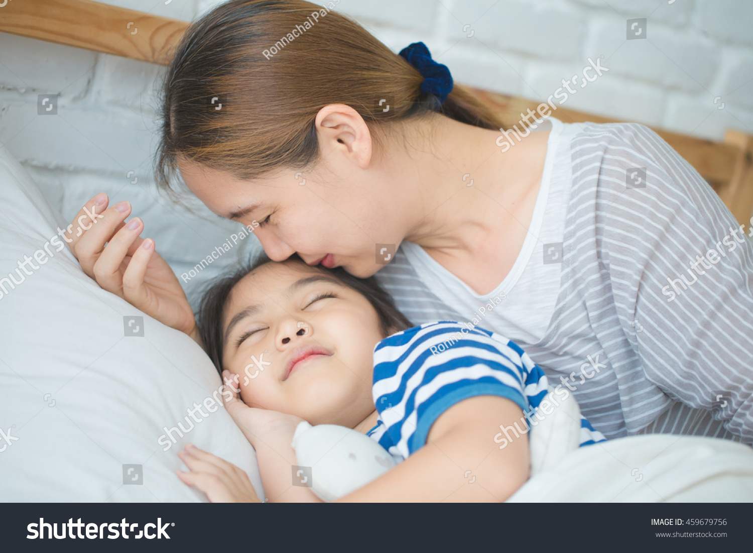 Asian Mother Kissing Her Daughter Goodnight Foto Stock Editar Agora