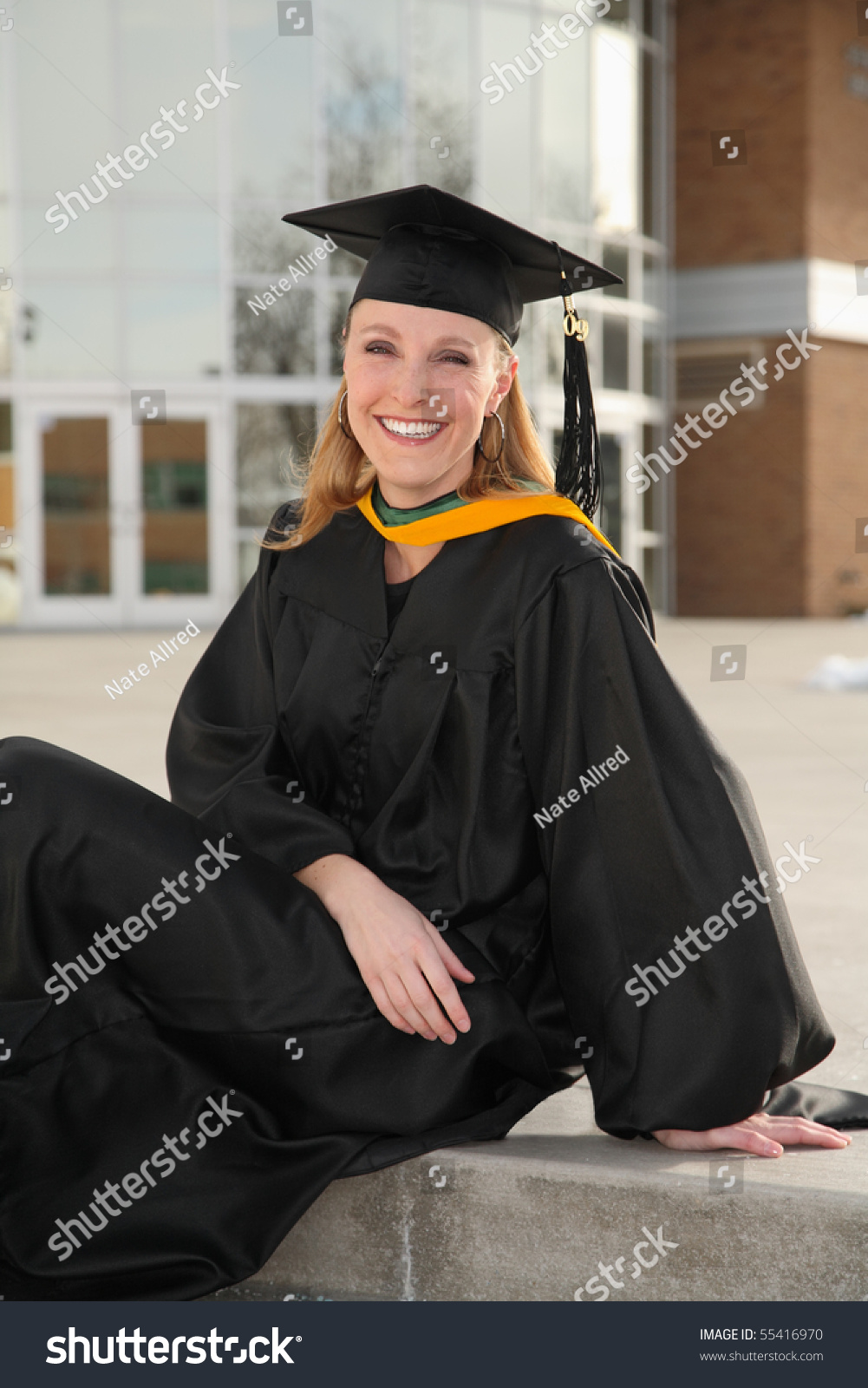 Attractive Blond Woman In Graduation Uniform Sitting In Front Of ...