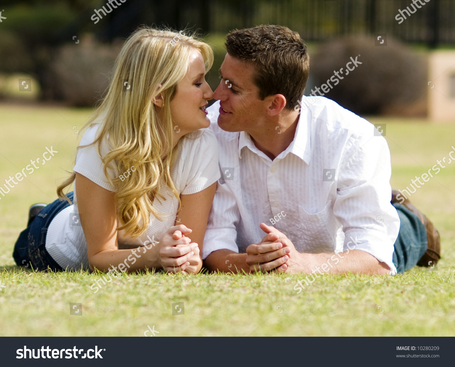 Attractive Couple Laying On The Grass In A Park On A Warm Spring Day ...