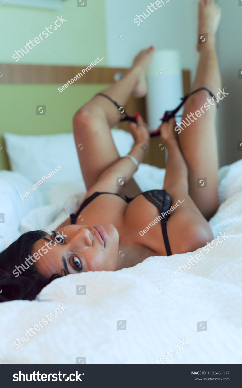 Attractive Indian woman in black lingerie poses against a floor length  window in natural light Stock Photo