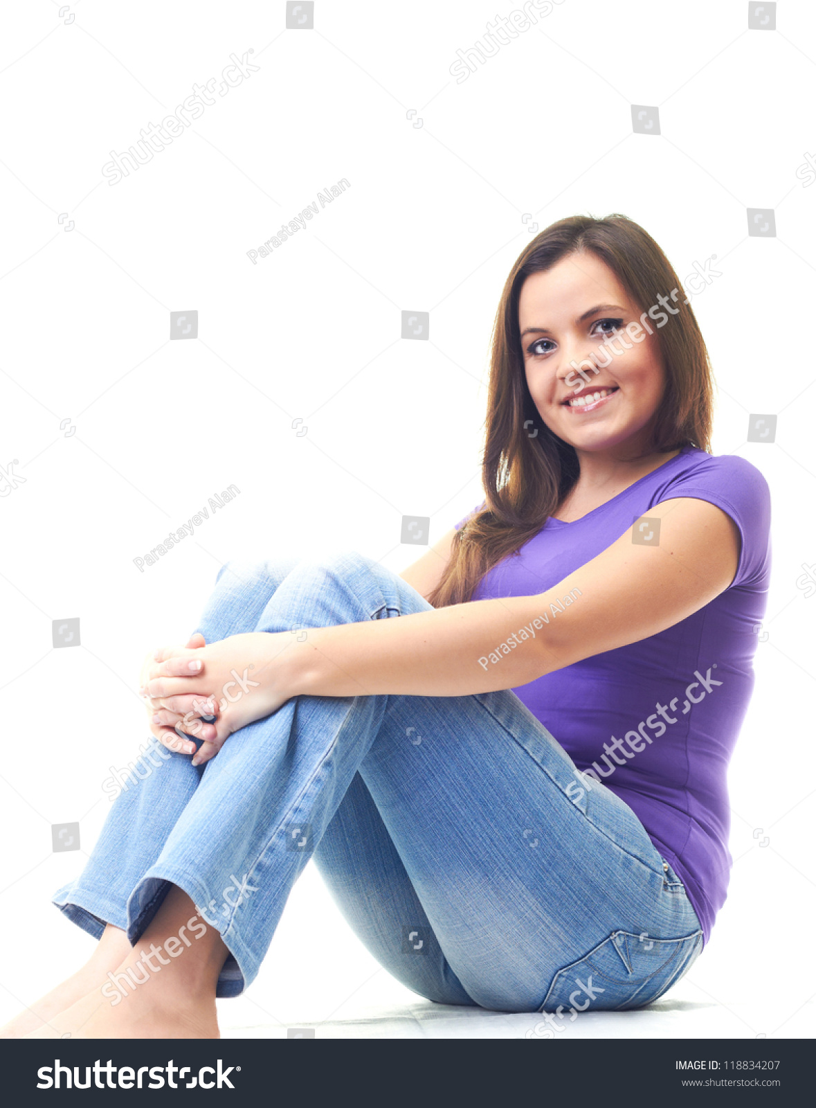 Attractive Smiling Young Woman In A Purple Shirt And Blue Jeans Sitting ...