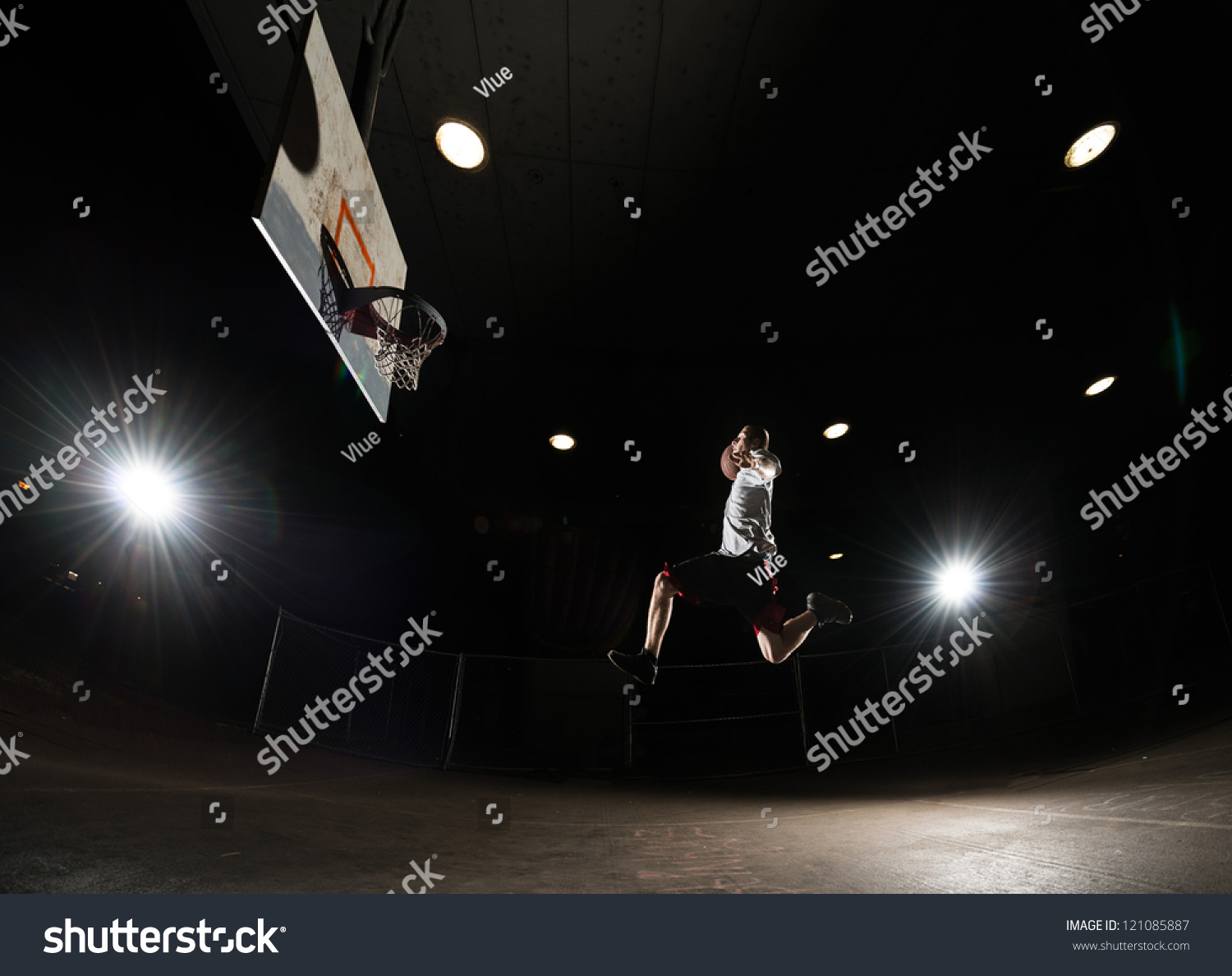 Basketball Player At Night Jumping And Aiming At Hoop With Lights On ...