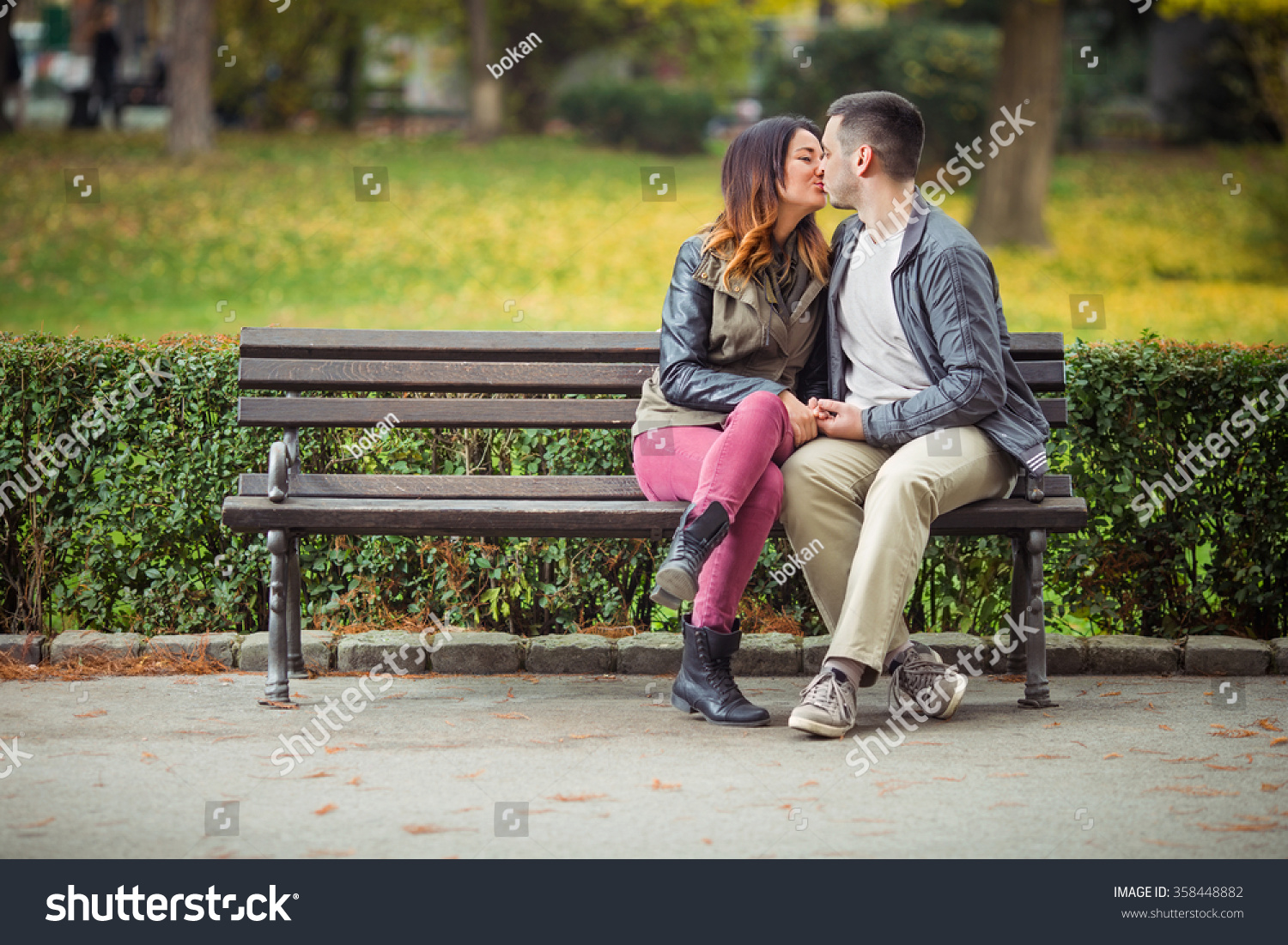 公園のベンチに座りながらキスをする美しい夫婦 の写真素材 今すぐ編集