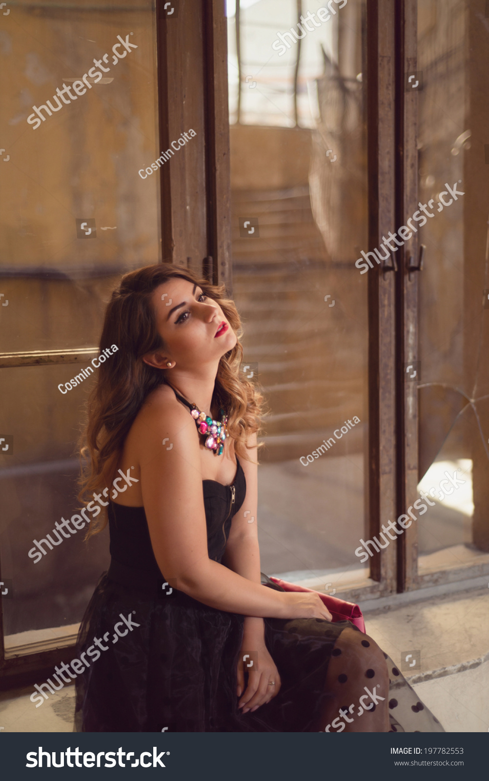 An alluring woman getting dressed in front of a window