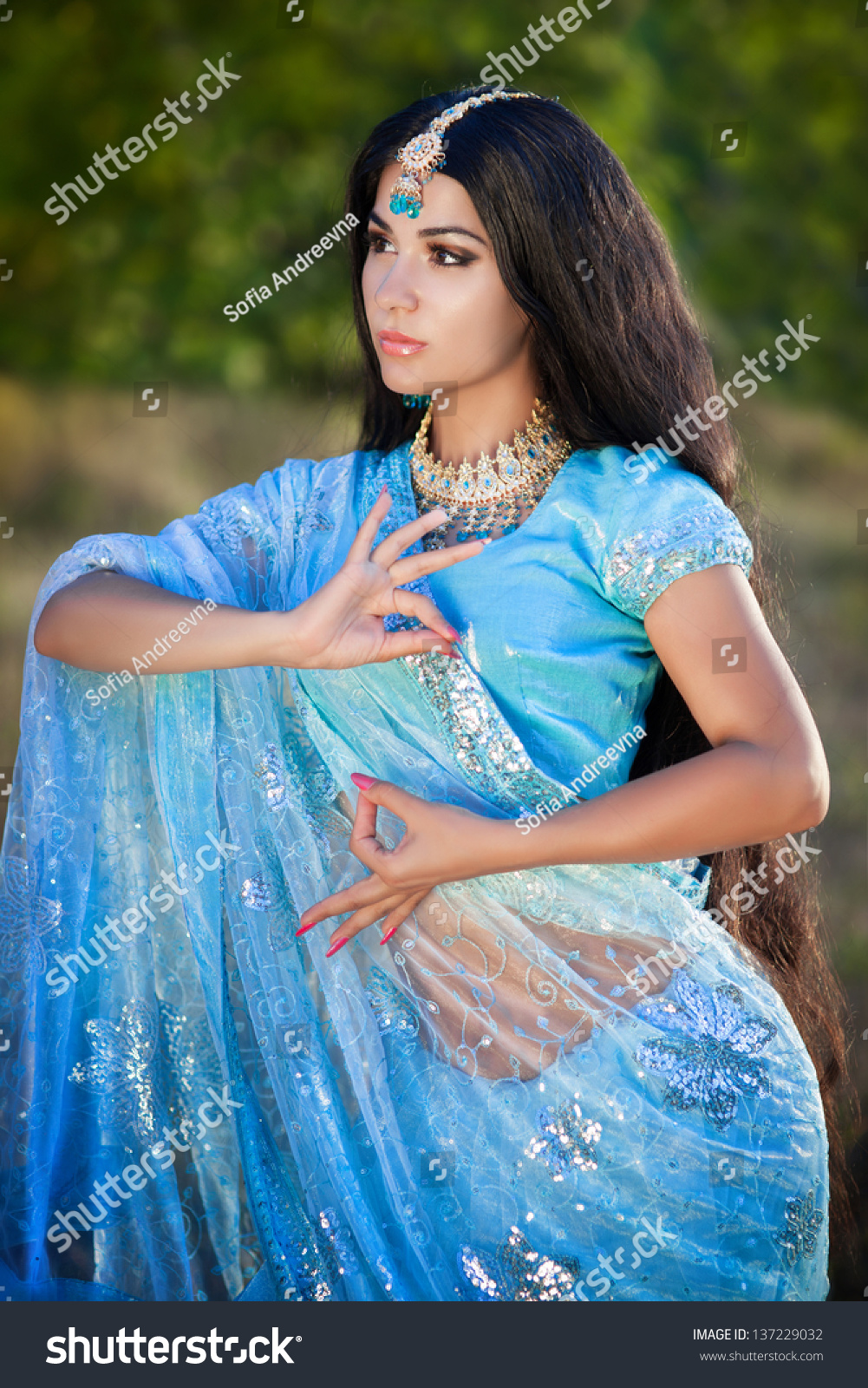 https://image.shutterstock.com/z/stock-photo-beautiful-indian-woman-bellydancer-dancing-bollywood-dance-in-sari-outdoors-brunette-indian-beauty-137229032.jpg