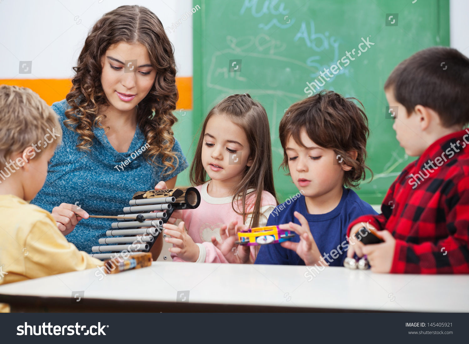 Beautiful Preschool Teacher Teaching Students To Play Xylophone In Class