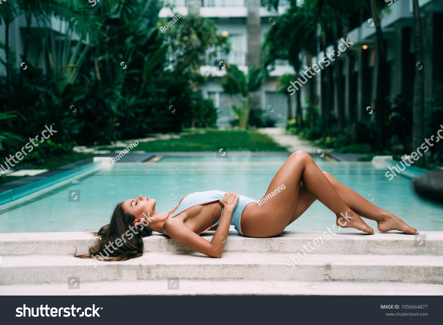 青いビキニの美しいセクシーな女性モデルは 夏休みにポーズをとって日焼けしたスイミングプールの近くに横たわる 健康体のケア の写真素材 今すぐ編集