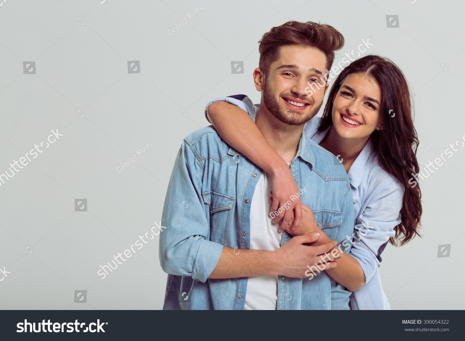 Beautiful Young Couple In Jeans Shirts Is Hugging, Smiling And Looking ...