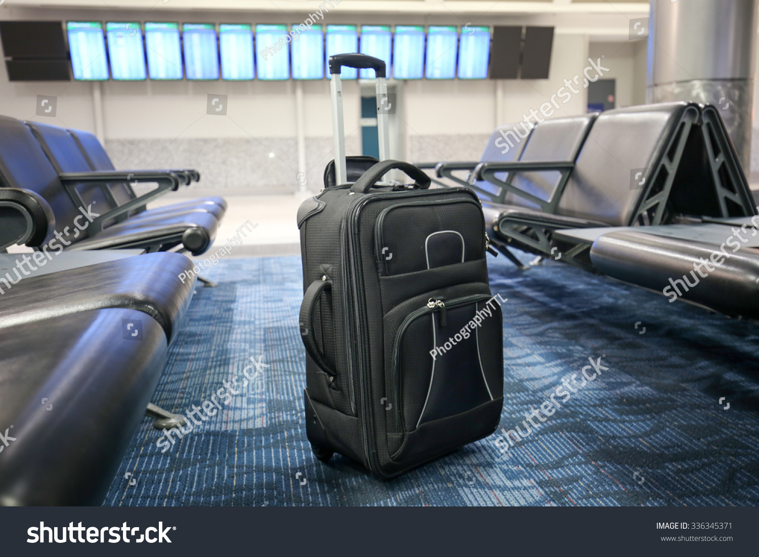 Black Suitcase Is Standing In An Airport Departure/Arrival Hall As If