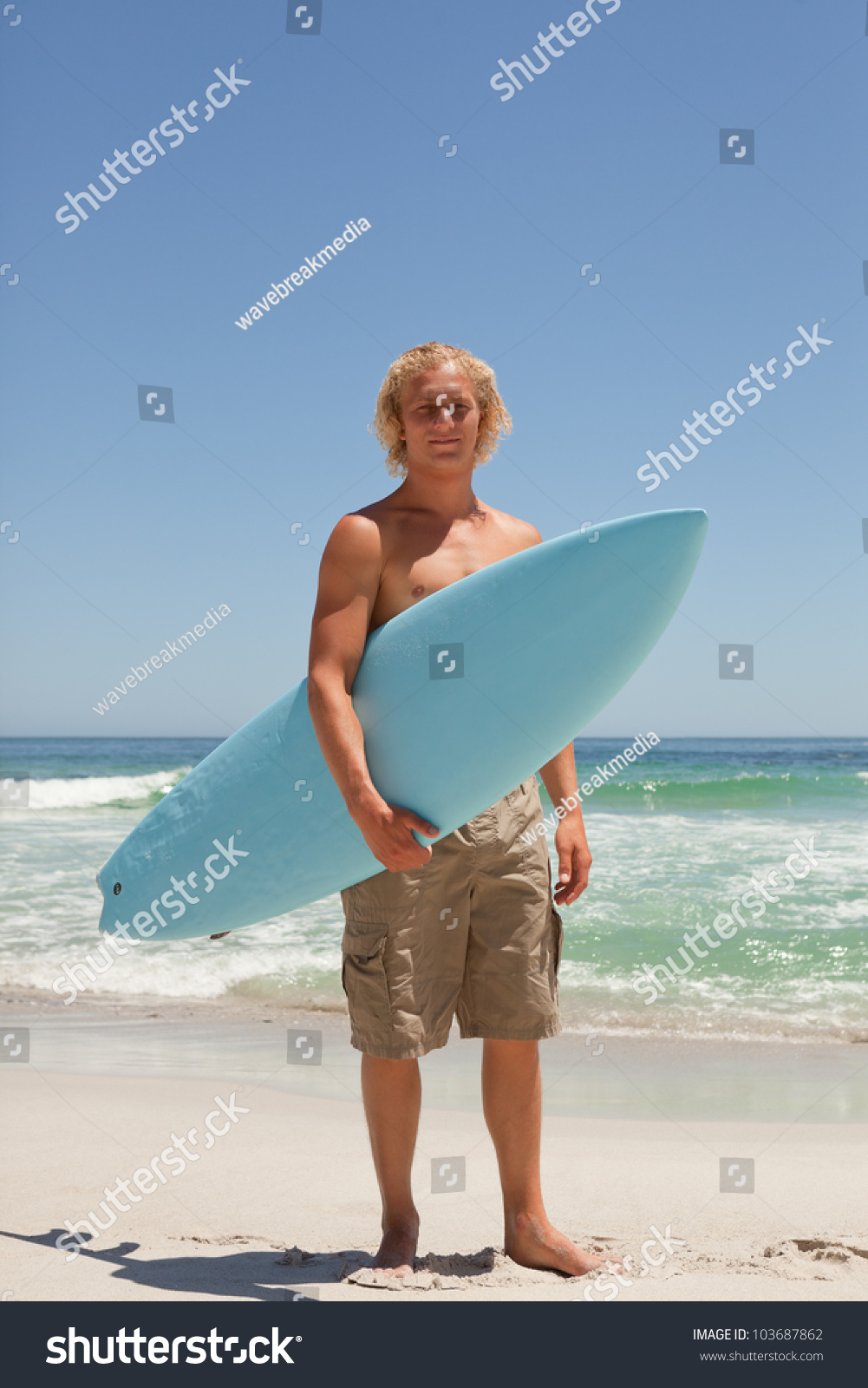 Blonde Man Holding His Blue Surfboard While Standing On The Beach Stock ...