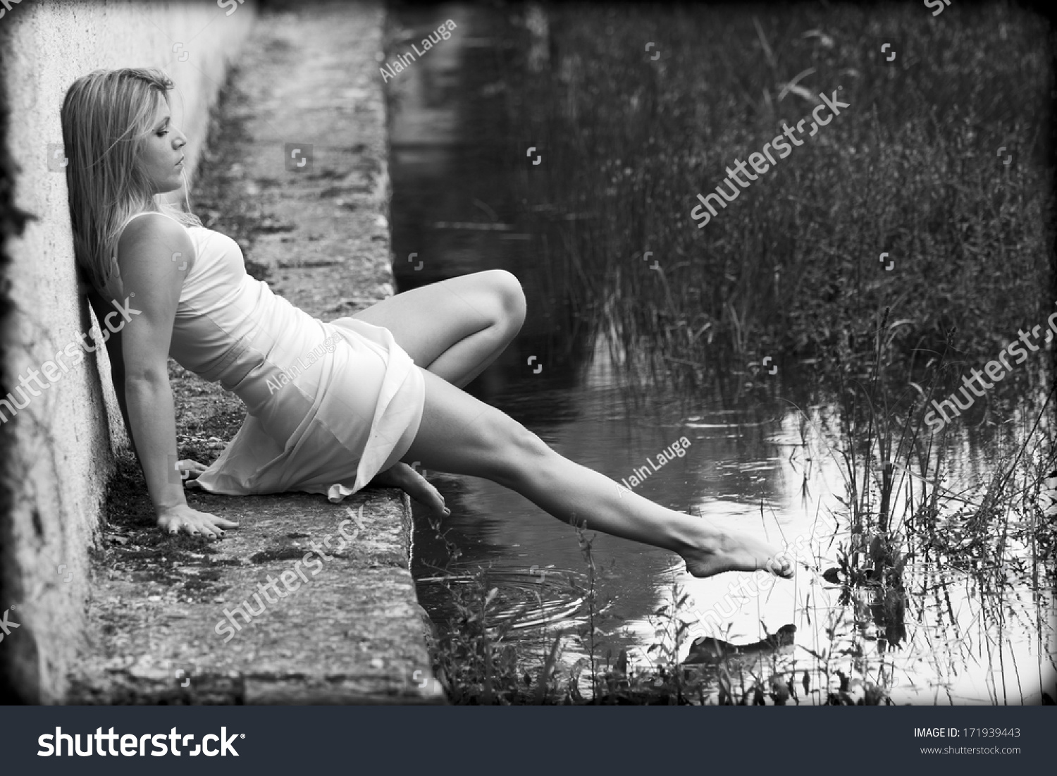 https://image.shutterstock.com/z/stock-photo-blonde-woman-wearing-a-white-dress-is-sitting-on-the-edge-of-a-pond-she-is-barefoot-she-tries-171939443.jpg