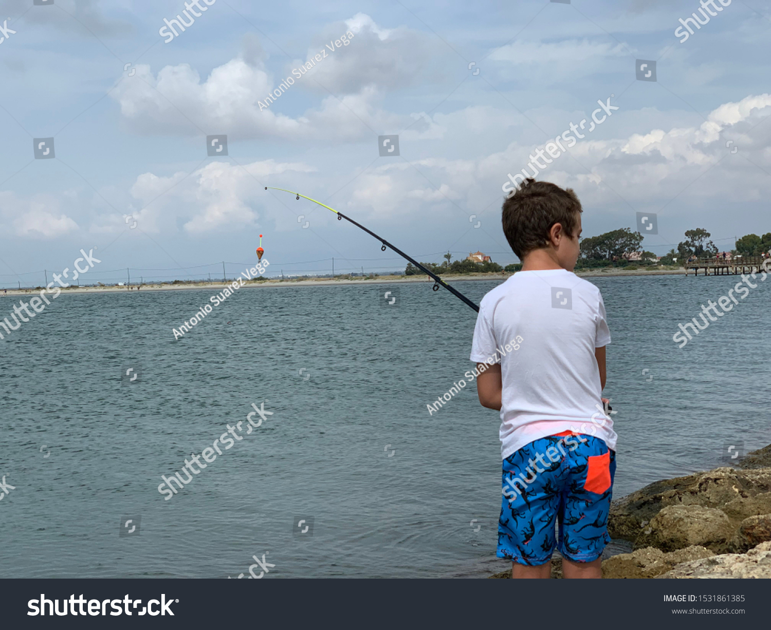 Boy Fishing On Breakwater Near Sea Stock Photo Edit Now