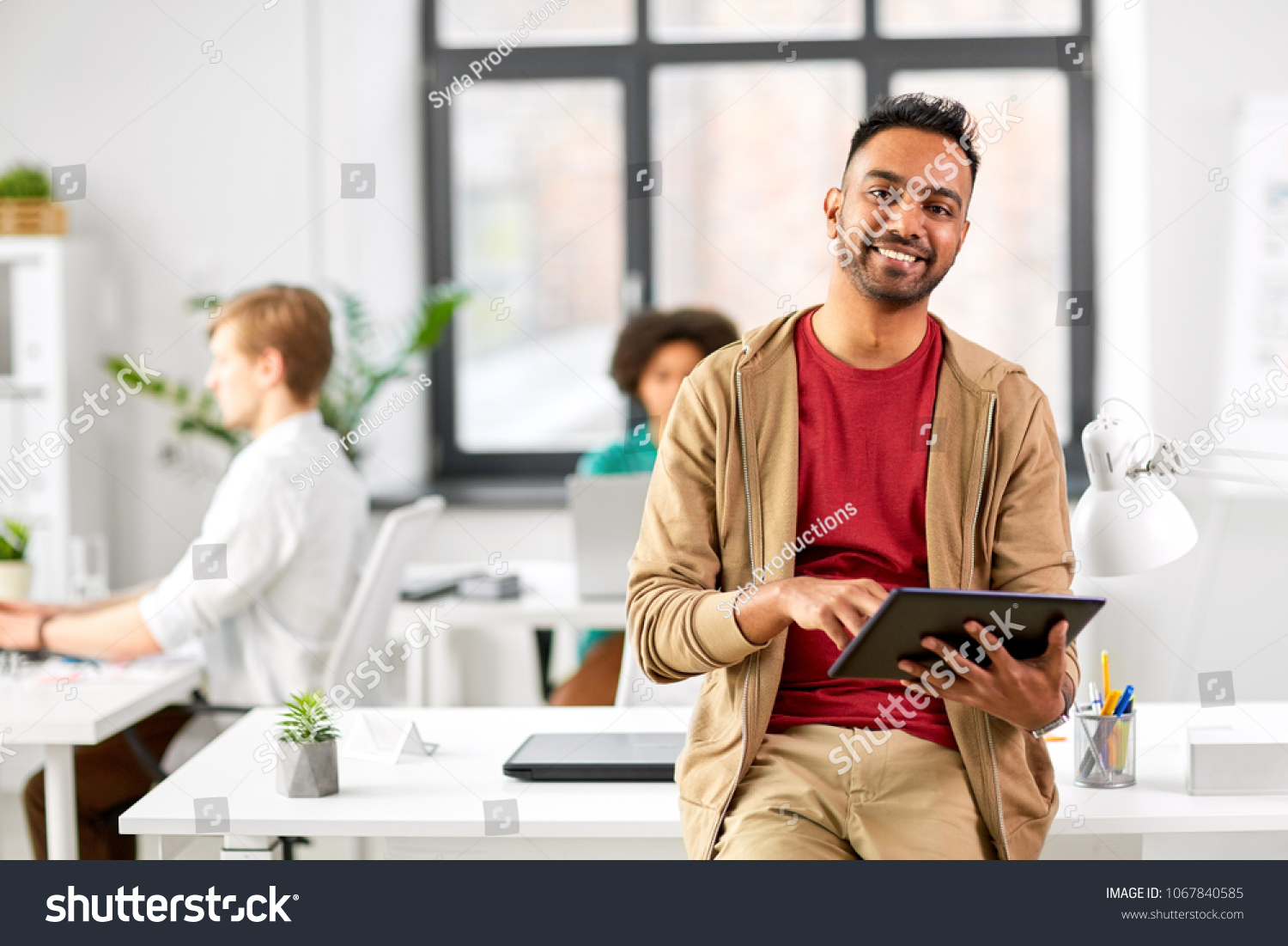 business, technology and people concept - happy smiling indian man with tablet pc computer at office