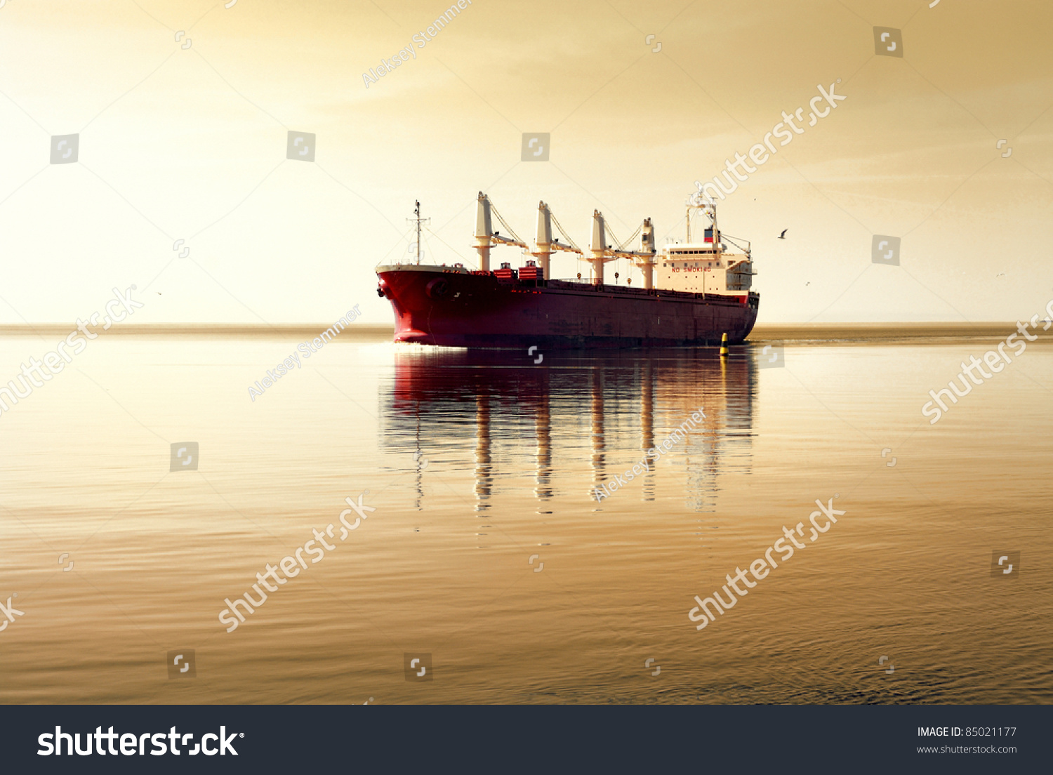 Cargo Ship Sailing In Still Water Against Sunset Sky Stock Photo ...