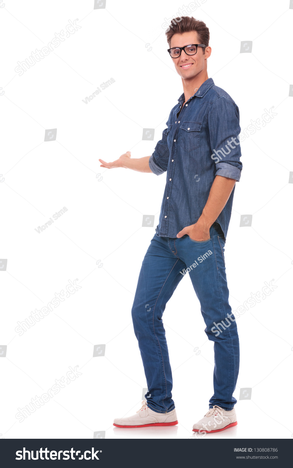 Casual Young Man Standing With A Hand In Pocket And Presenting ...