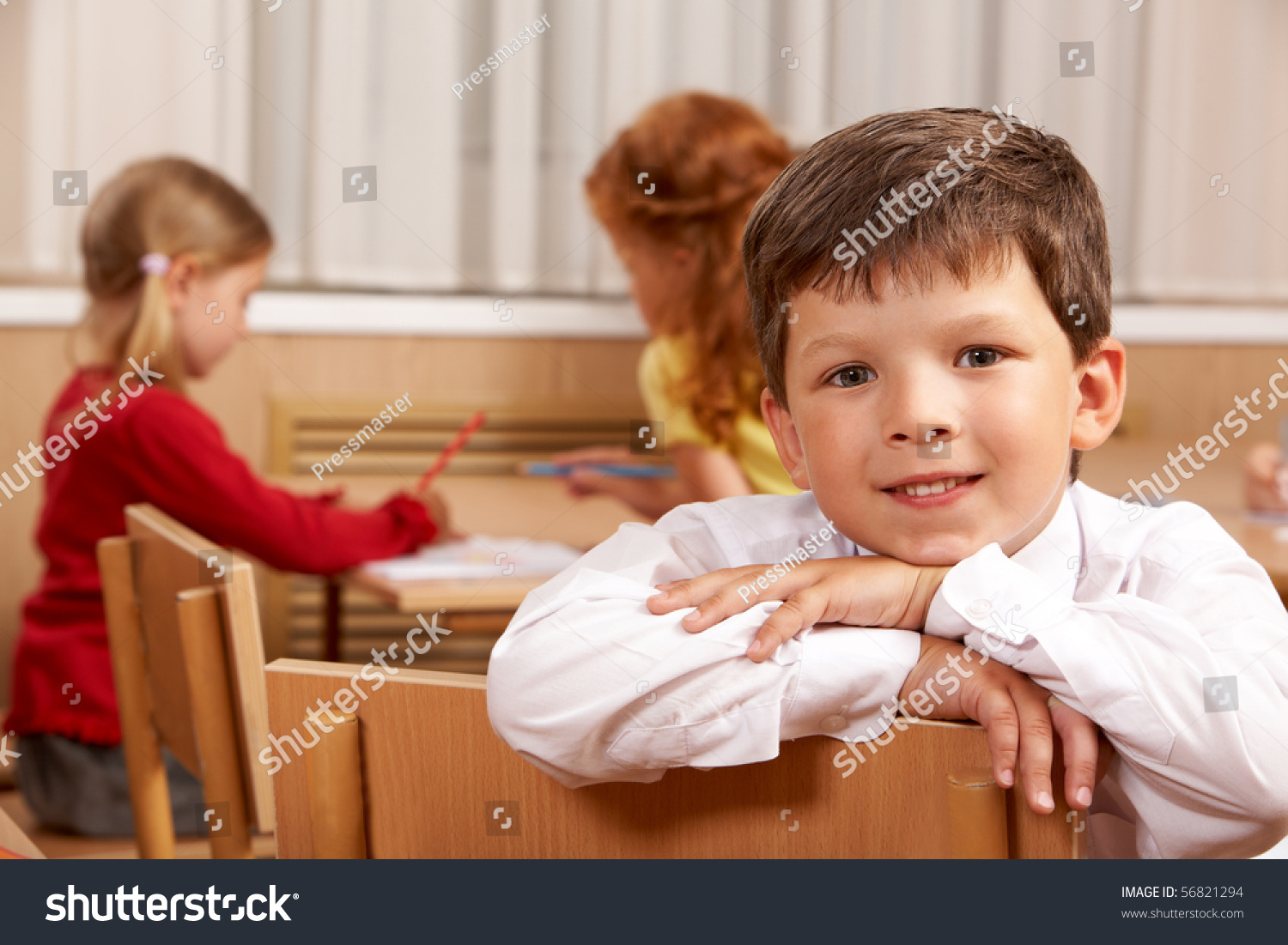 Clever Schoolboy Looking At Camera In Classroom With His Classmates At ...