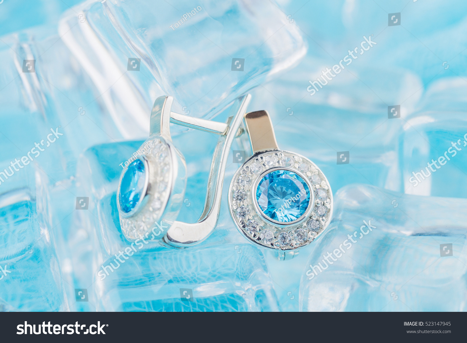 https://www.shutterstock.com/pic-523147945/stock-photo-close-up-earrings-with-zircon-and-expensive-blue-gemstones-still-life-on-ice-blue-background.html